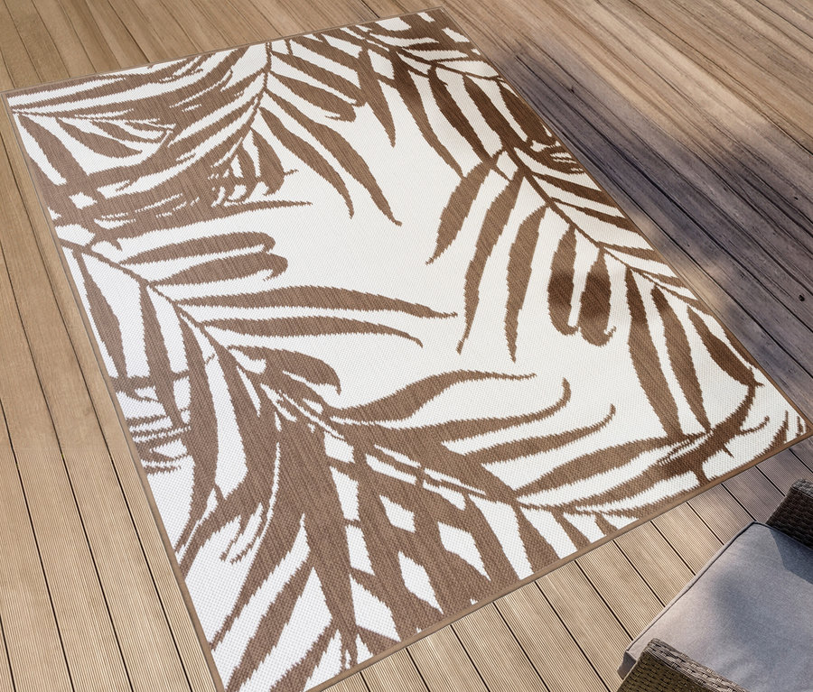 Ein brauner Outdoor-Wendeteppich »Palm Tree« liegt auf einer Holzterrasse.