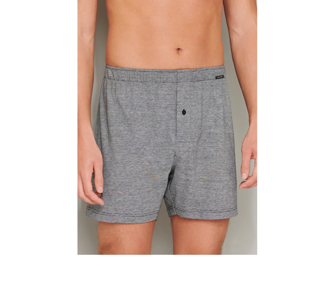 Mann trägt graue SCHIESSER Boxershorts aus Baumwolle mit Gummibund und Knopfleiste.