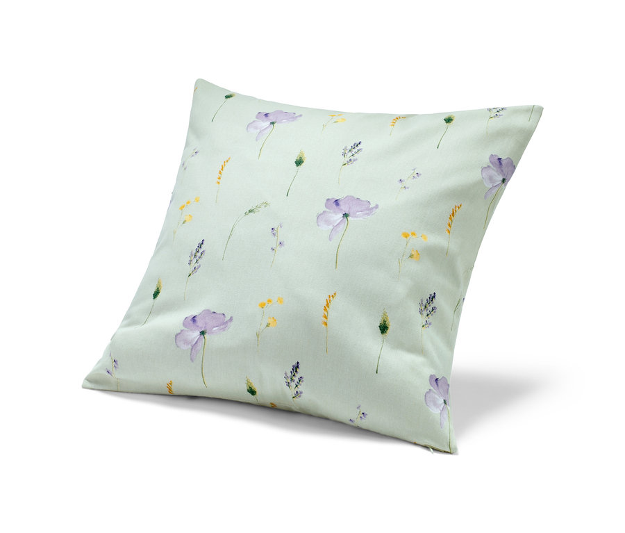 Ein Deko-Kissenbezug mit einem Muster aus lila und gelben Blumen auf hellgrünem Hintergrund.