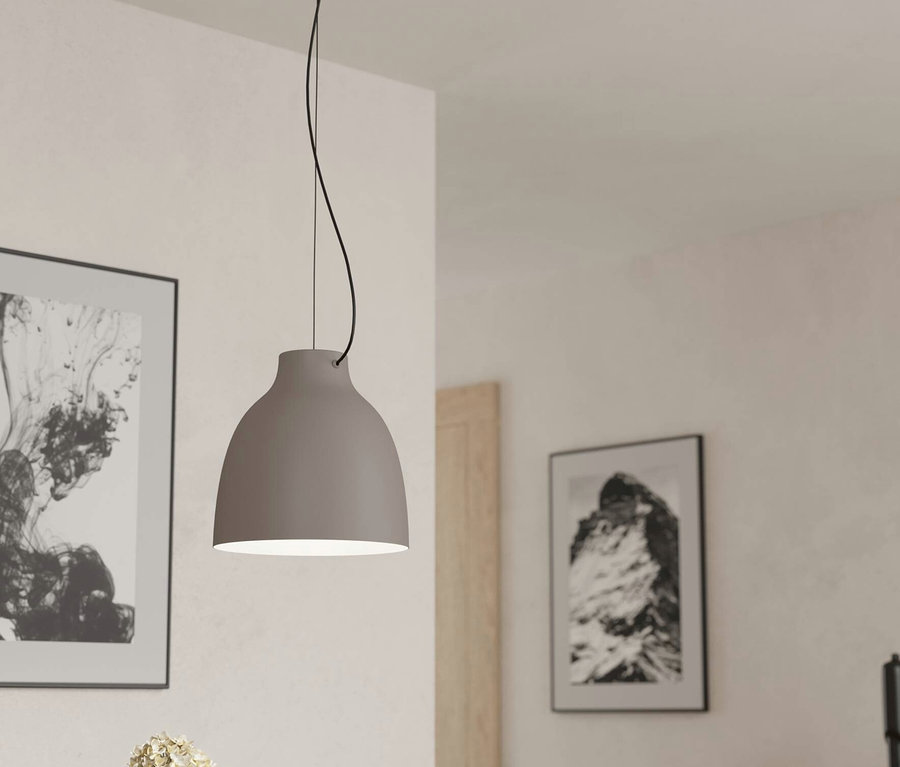 Graue Hängelampe über einem Tisch mit Blumen und Bildern an der Wand.