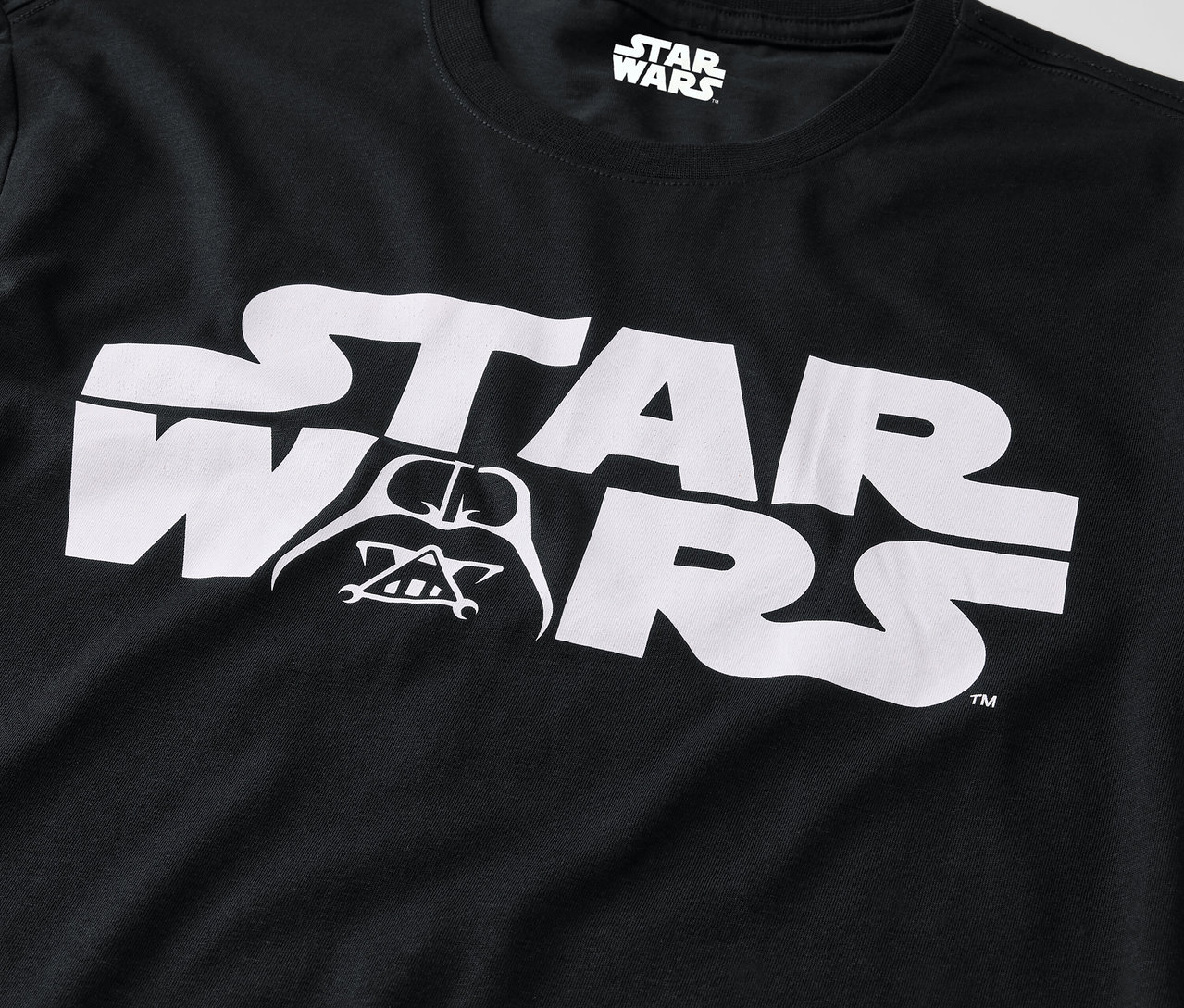 Schwarzes T-Shirt mit weißem Star Wars Logo und Darth Vader Bild.