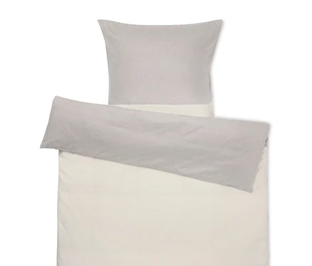 Beige Bettwäsche mit grauem Kissen oben.