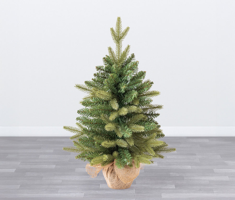 Kleiner grüner Weihnachtsbaum in einem Jutesack.