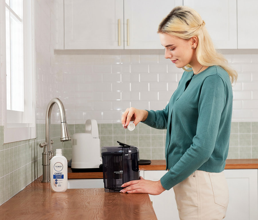 Frau gibt Tineco i Carpet Spot Reinigungslösung in den Wassertank.