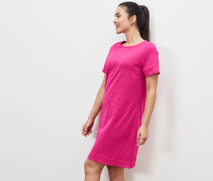 Frau steht seitlich in einem pinken Jerseykleid.