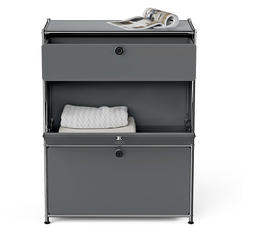 Graue Kommode mit zwei Schubladen, die obere Schublade ist offen, auf der Oberseite liegt eine Zeitschrift.