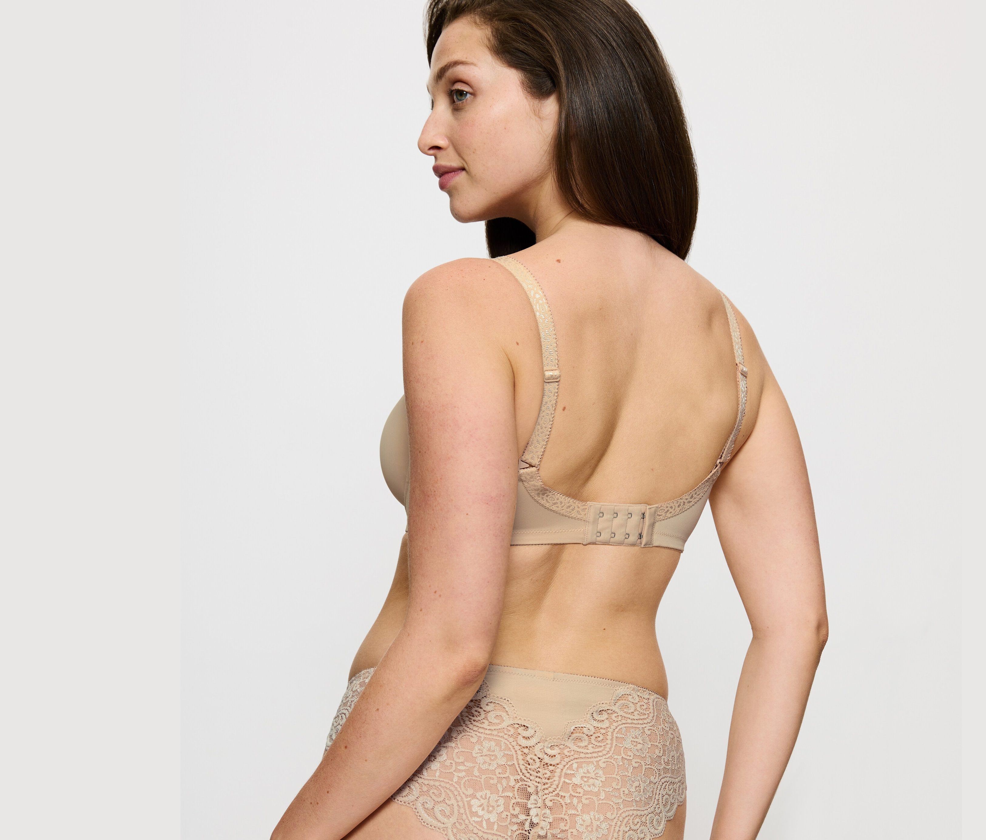 Frau posiert in Triumph Amourette Minimizer-BH, hautfarben, und Spitzenhöschen.