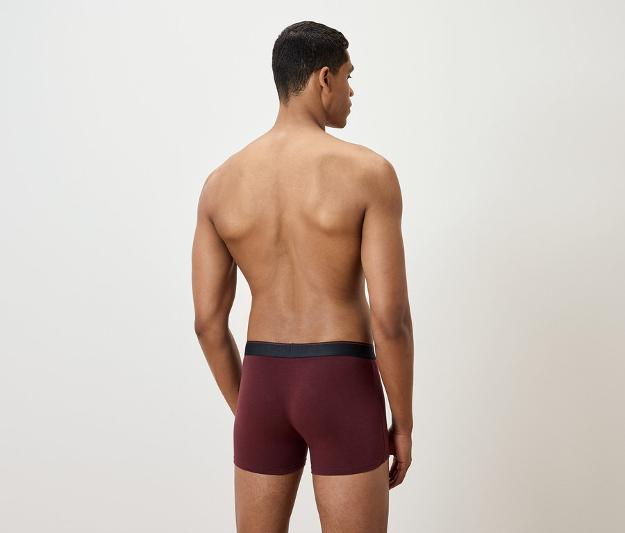 Mann von hinten trägt weinrote Boxershorts.