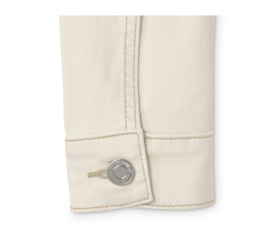 Detailansicht einer cremeweißen Jeansjacke mit Knopf.