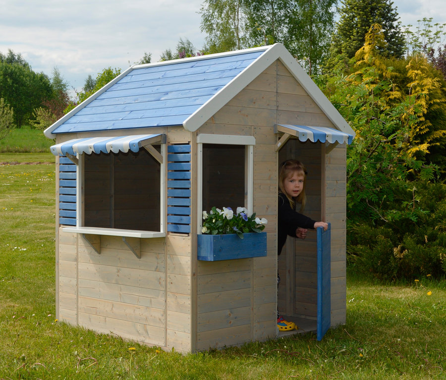 Mädchen schaut aus dem Wendi-Spielhaus »Maritime House« auf einer Wiese.