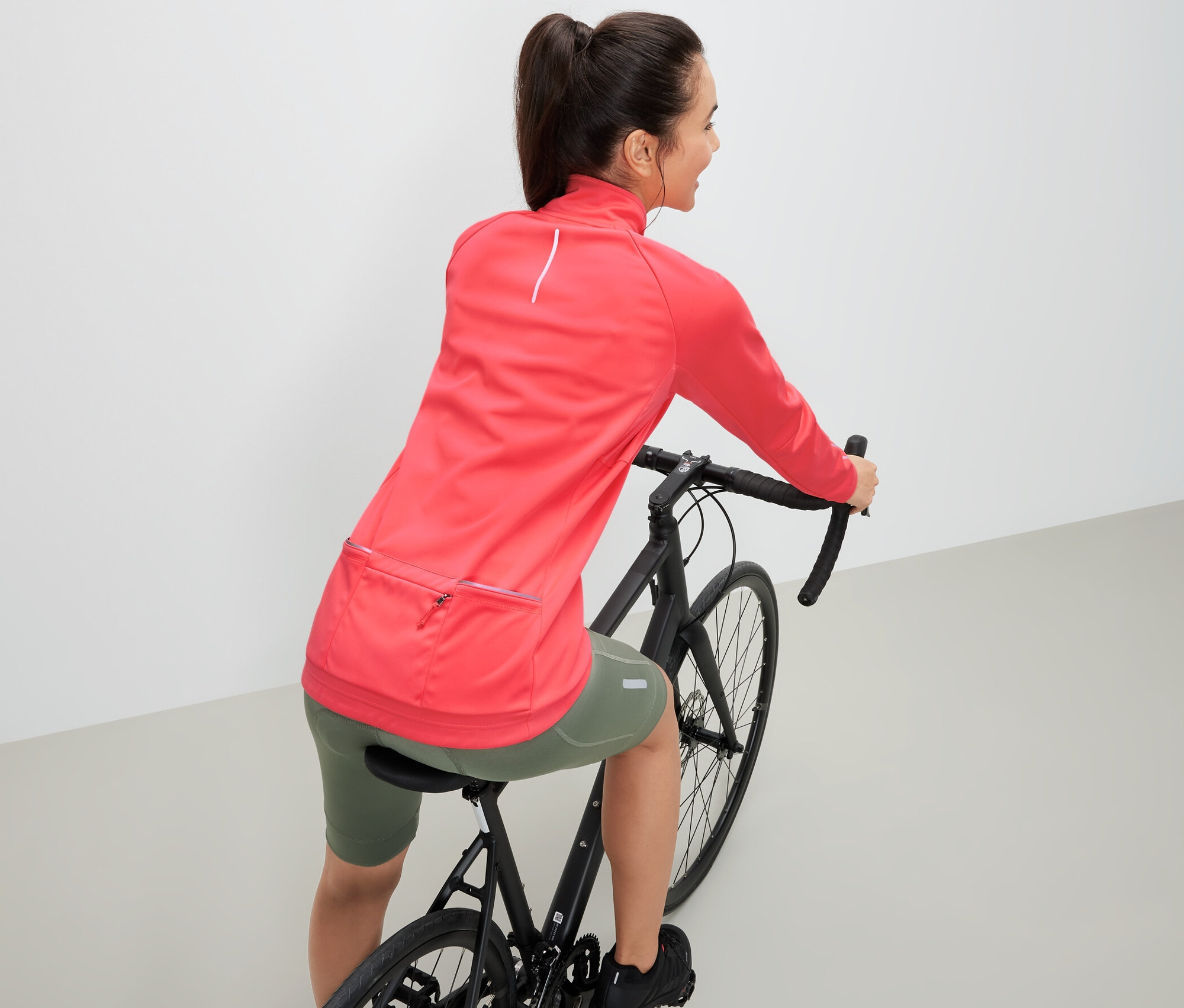 Frau auf einem Fahrrad trägt eine Fahrrad-Funktionsjacke.