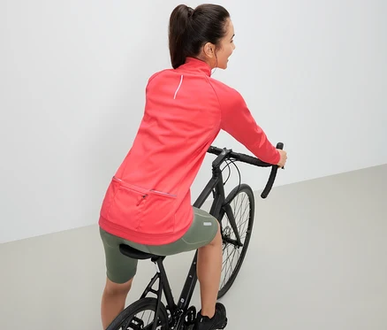 Frau auf einem Fahrrad trägt eine Fahrrad-Funktionsjacke.
