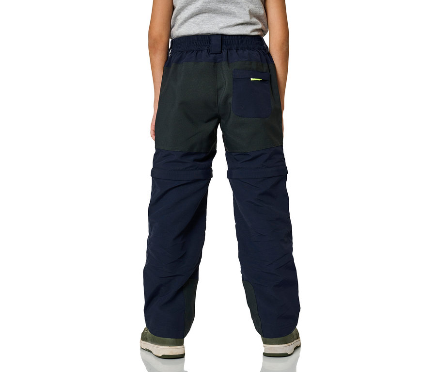 Junge steht mit dem Rücken zur Kamera und trägt eine marineblaue Jako-O Zipp-off Hose.