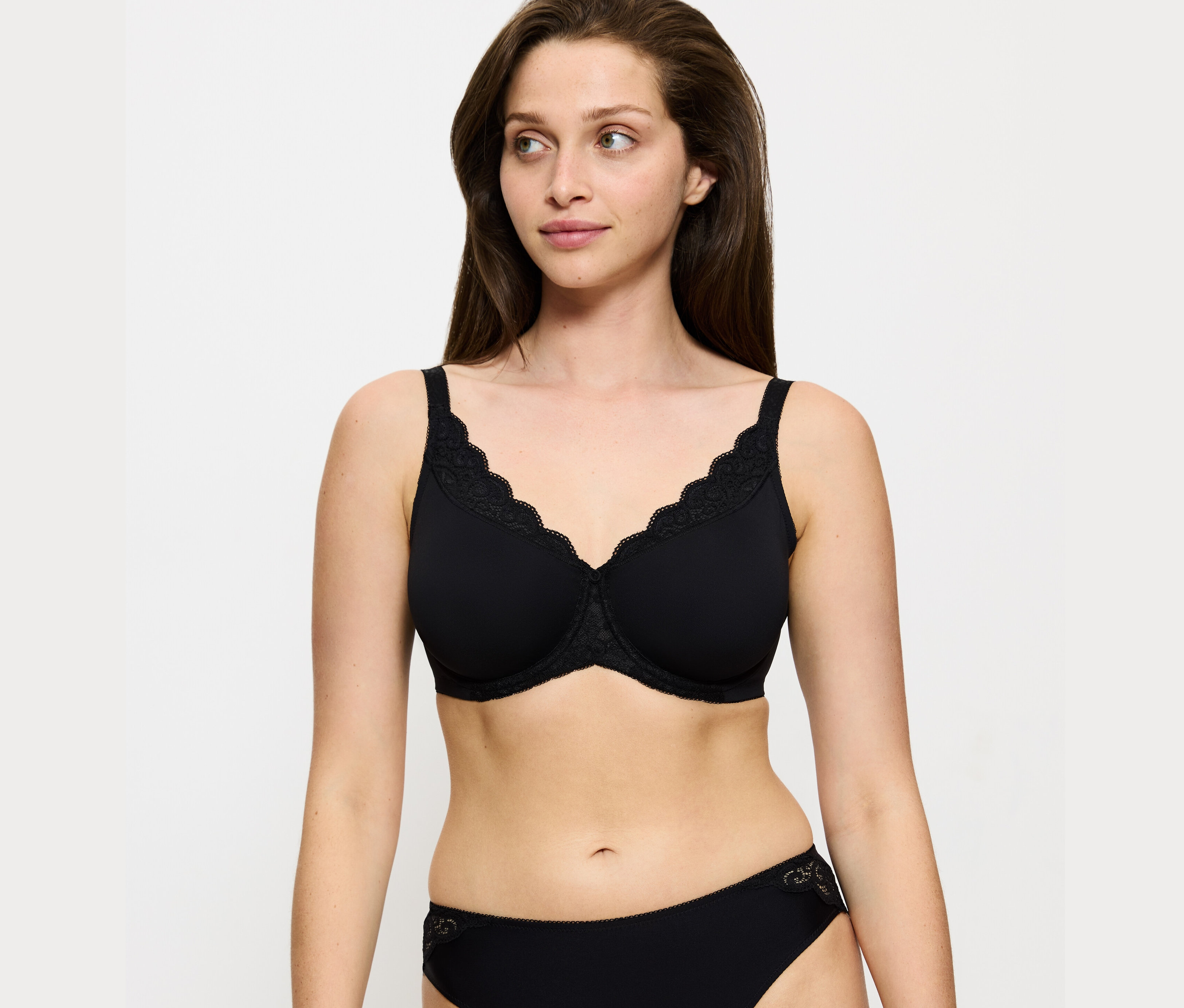 Frau trägt einen schwarzen Triumph Amourette Minimizer-BH und eine schwarze Unterhose.