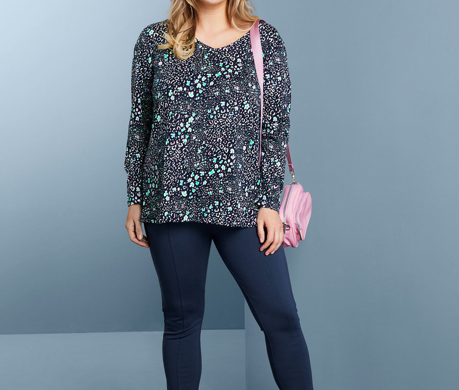 Frau posiert in Langarmshirt, Bodyforming-Jerseyhose, Slip-on-Sneaker und Umhängetasche.