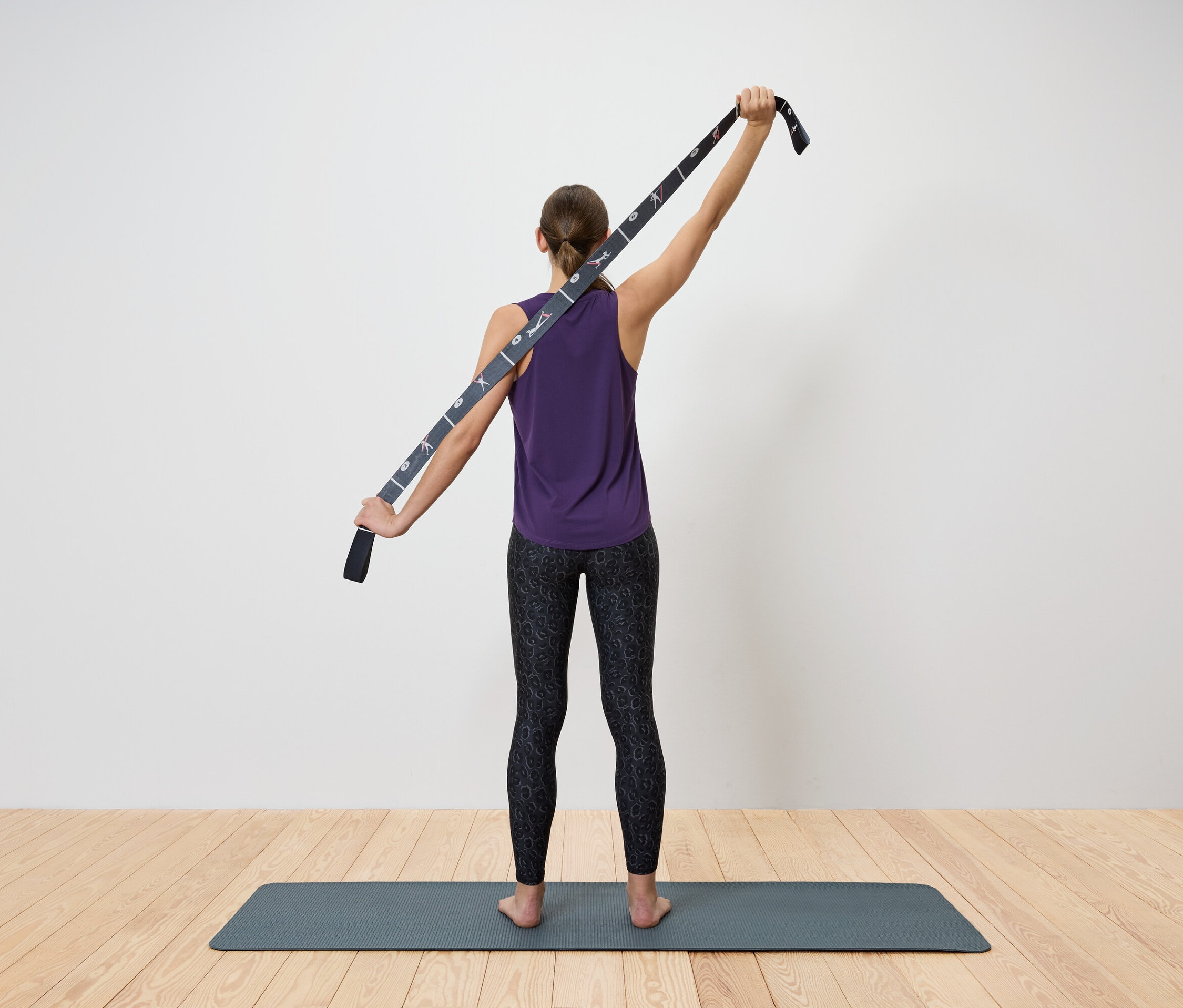 Frau dehnt den Oberkörper mit einem Yogagurt.