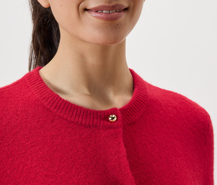 Detailaufnahme einer Frau, die einen roten Cardigan trägt.