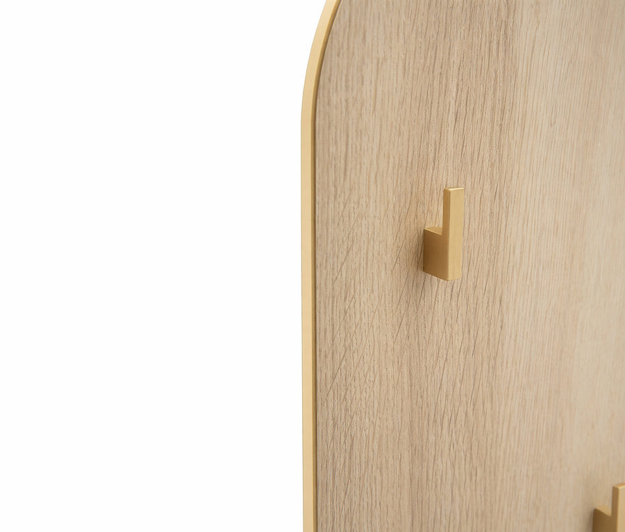 Nahaufnahme eines goldenen Hakens an einer hellbraunen Holzplatte mit goldenem Rahmen.