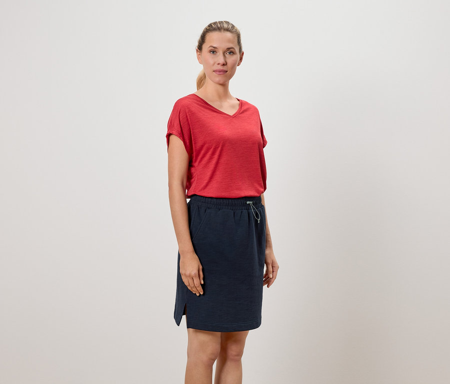 Frau trägt ein rotes T-Shirt und einen marineblauen Rock.