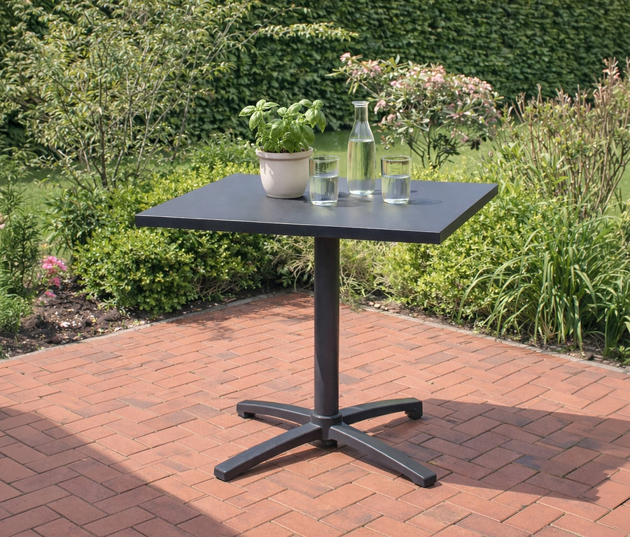 Auf einer Terrasse steht ein schwarzer Bistrotisch mit Topfpflanze, Wasserflasche und Gläsern.