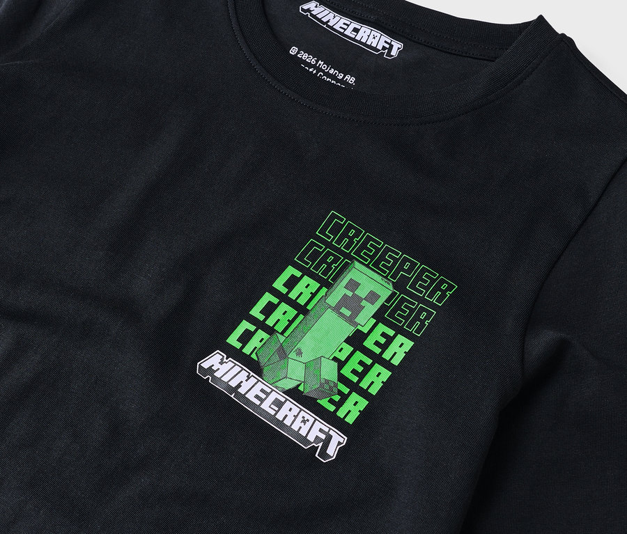 Nahaufnahme eines schwarzen Langarmshirts mit einem grünen Minecraft-Creeper-Design.