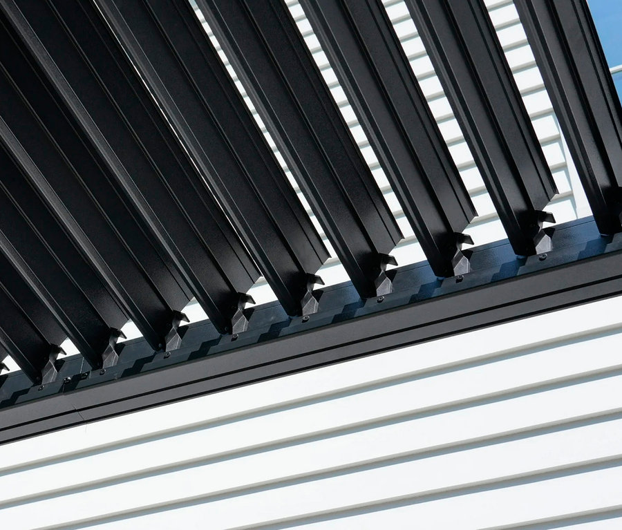 Schwarze Lamellen sind mit Halterungen an einer weißen Wand befestigt.