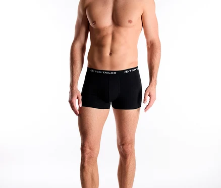 Ein lächelnder Mann trägt schwarze TomTailor Slipboxer „Buffer“ mit TomTailor-Schriftzug am Bund und blickt nach unten.