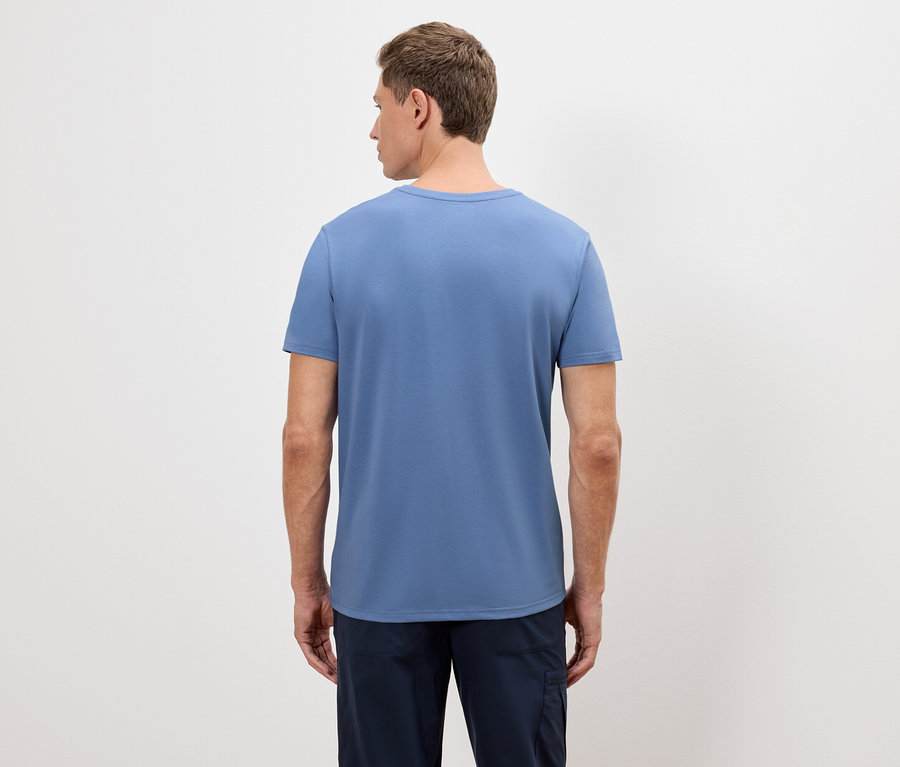 Ein Mann steht mit dem Rücken zur Kamera und trägt ein blaues T-Shirt und eine marineblaue Hose.