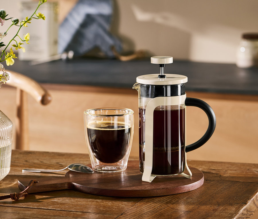Eine Siebstempelkanne, 300 ml, 2 Tassen, friendly beige und eine Tasse Kaffee auf einem Holztisch.