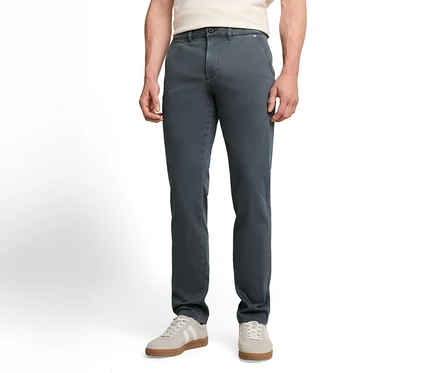 Eine Person trägt eine dunkelgraue Chinohose, ein helles T-Shirt und hellgraue Sneaker mit weißen Streifen.