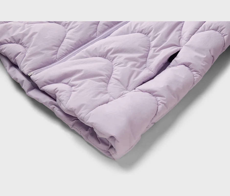 Nahaufnahme einer hellvioletten Steppjacke mit Reißverschluss und Seitentasche.