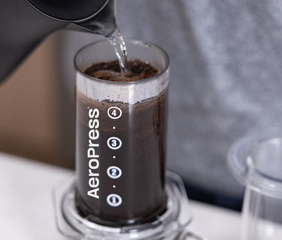 Wasser wird in einen transparenten AeroPress Coffee Maker »Clear« gegossen.