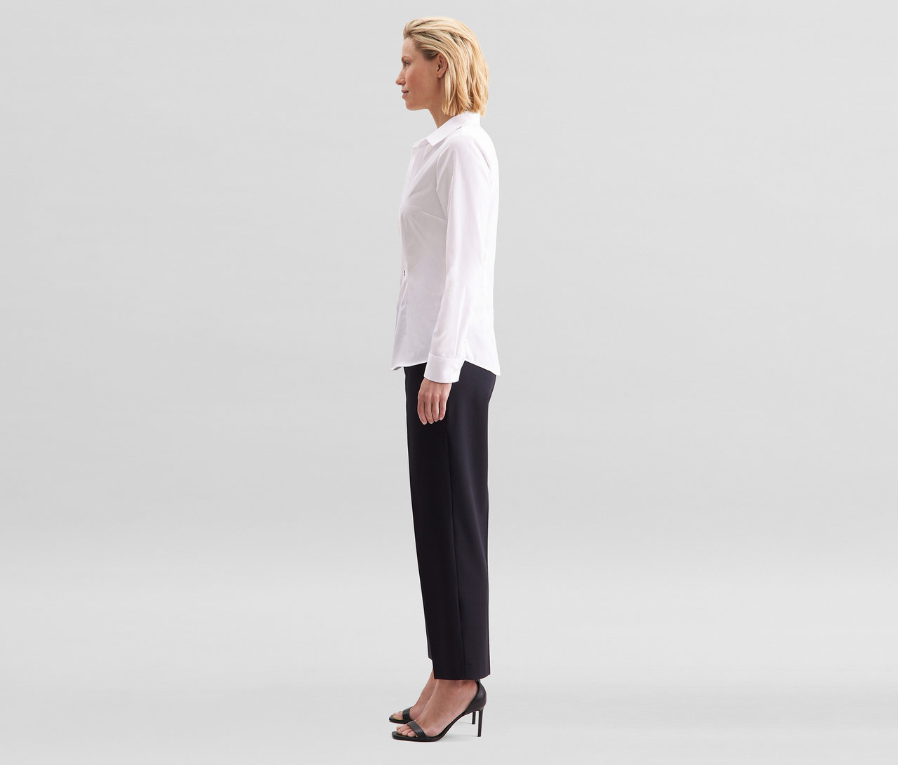Frau im Profil, trägt eine weiße Seidensticker Bluse Slim Fit non iron und schwarze Hose.