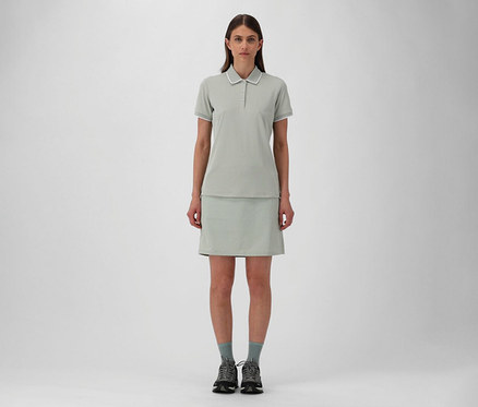 Frau in CMP Damen-Outdoor-Rock und pistazienfarbenem CMP Damen-Poloshirt aus Stretch-Piqué, dazu graue Socken und Wanderschuhe.