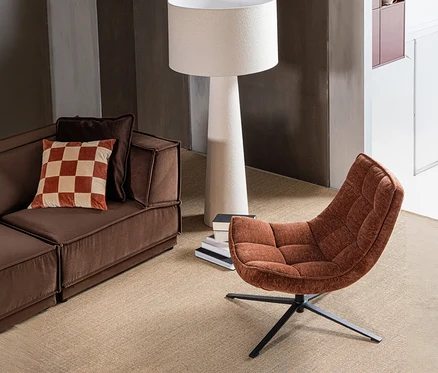 Braunes Sofa mit kariertem Kissen, daneben ein WOOOD Drehsessel "Maudi" in Braun und eine weiße Stehlampe auf beigem Teppich.
