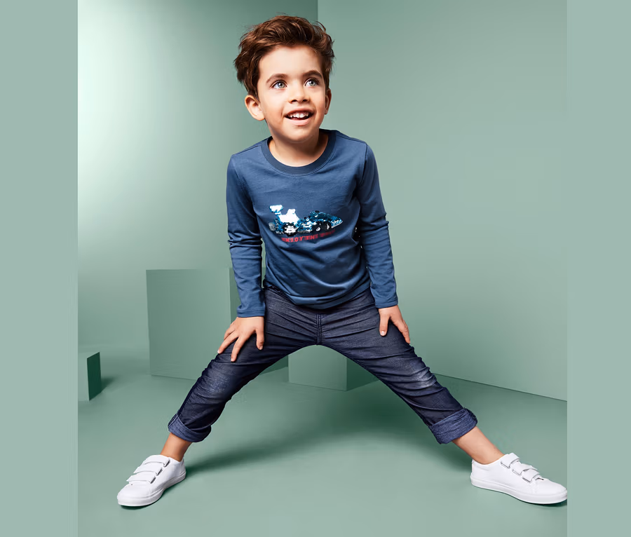 Junge posiert in Langarmshirt mit Wendepailletten.