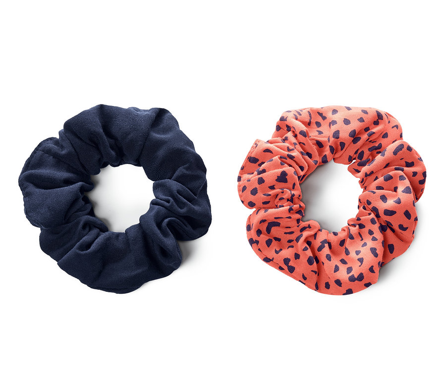 Zwei Scrunchies, eines marineblau und eines korallenfarben mit marineblauen Tupfen, liegen nebeneinander auf einem weißen Hintergrund. Die 2 Scrunchies.