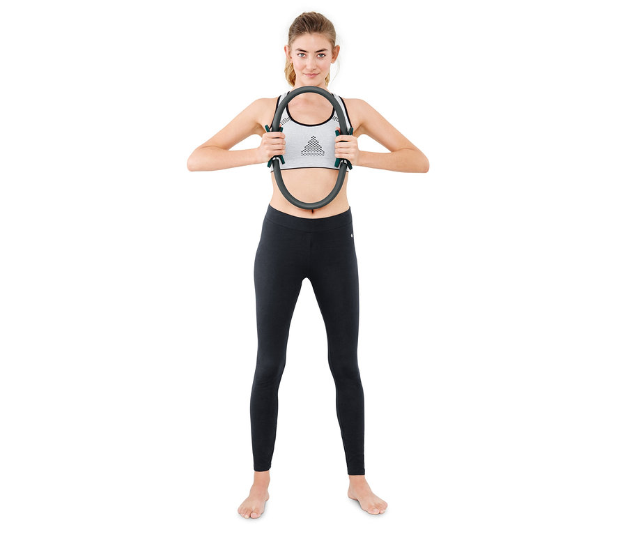 Frau hält Pilatesring vor ihrer Brust.