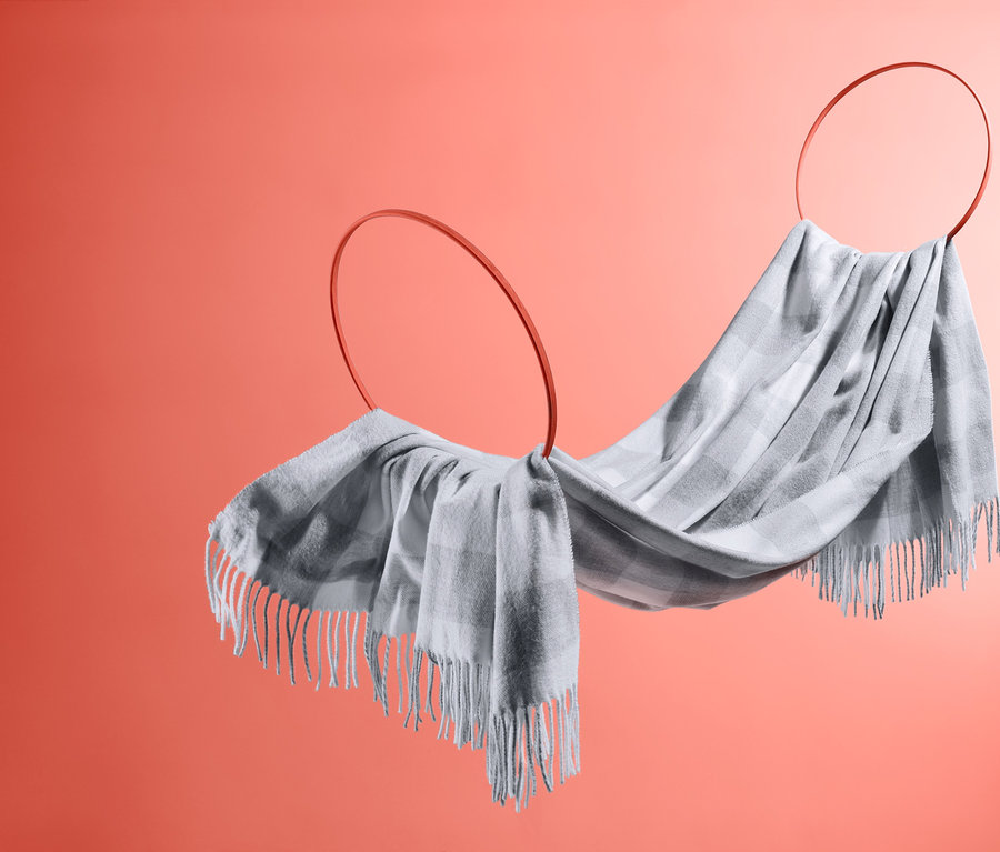 Eine karierte Wohndecke mit Fransen, die über zwei Ringe drapiert ist.