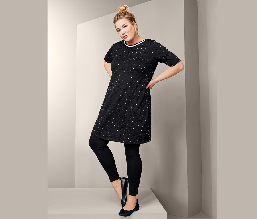 Frau posiert in schwarzen Leggings, Leder-Ballerinas und Jerseykleid im Punkte-Dessin.