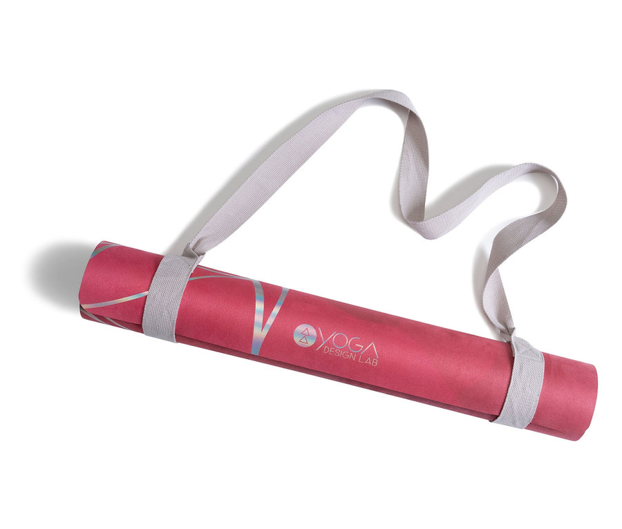 Eine zusammengerollte rosa Yogamatte mit Yoga Design Lab-Logo und grauem Gurt.
