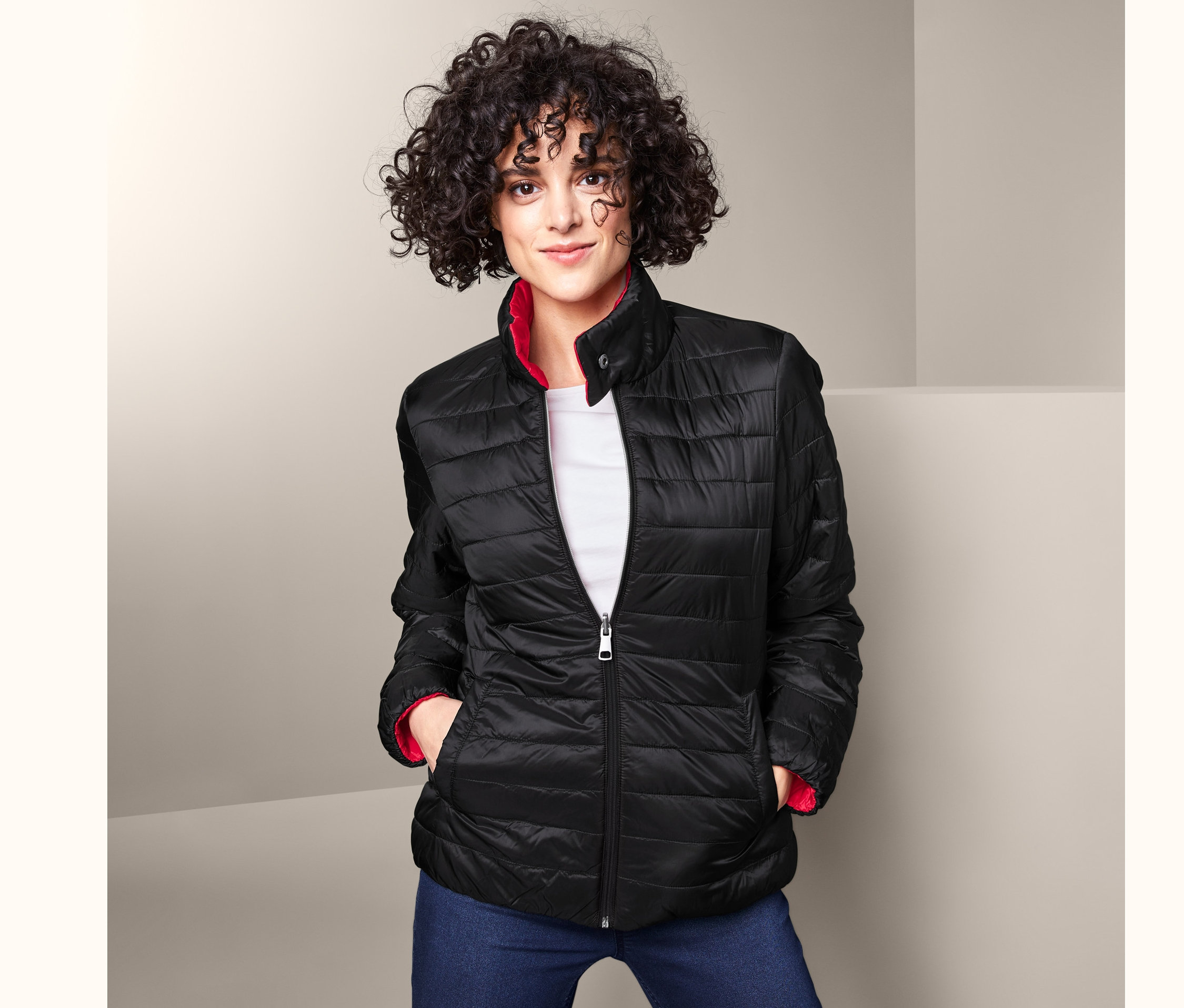 Frau trägt eine Wende-Steppjacke, Jeans und ein weißes T-Shirt.