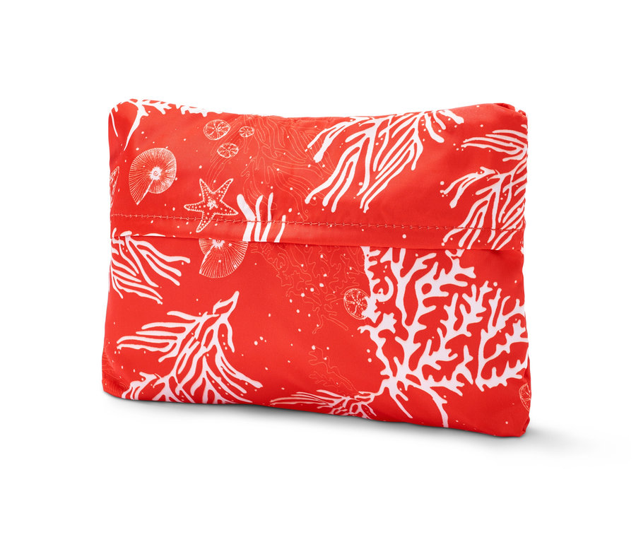 Eine faltbare Strandtasche mit Korallenmuster auf rotem Hintergrund.