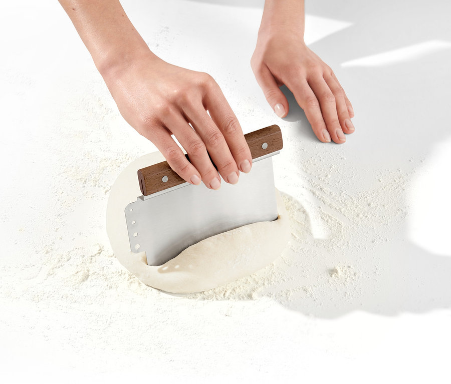 Hände schneiden Teig mit 2-in-1-Teigschneider.