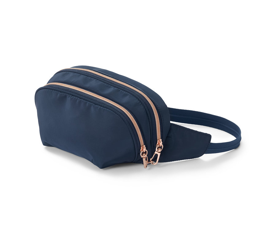 Eine marineblaue Sicherheits-Bauchtasche mit roségoldenen Reißverschlüssen liegt auf einer weißen Oberfläche.