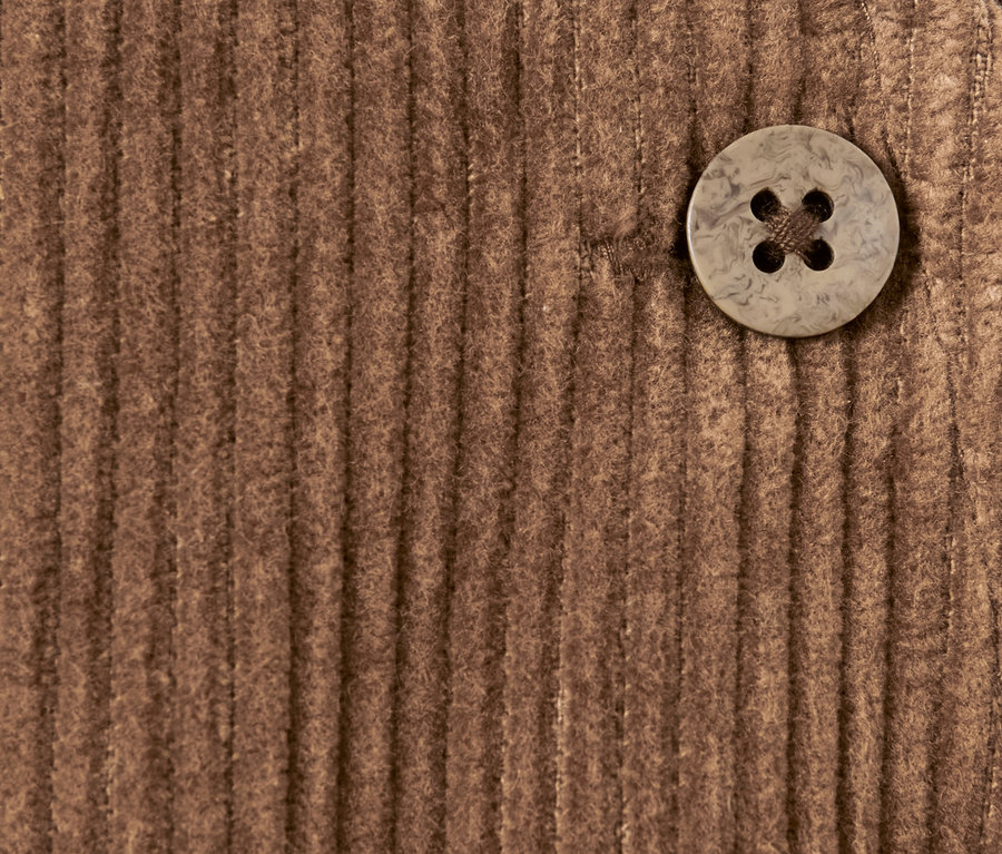 Detailaufnahme einer braunen Cord-Latzhose mit Knopf.