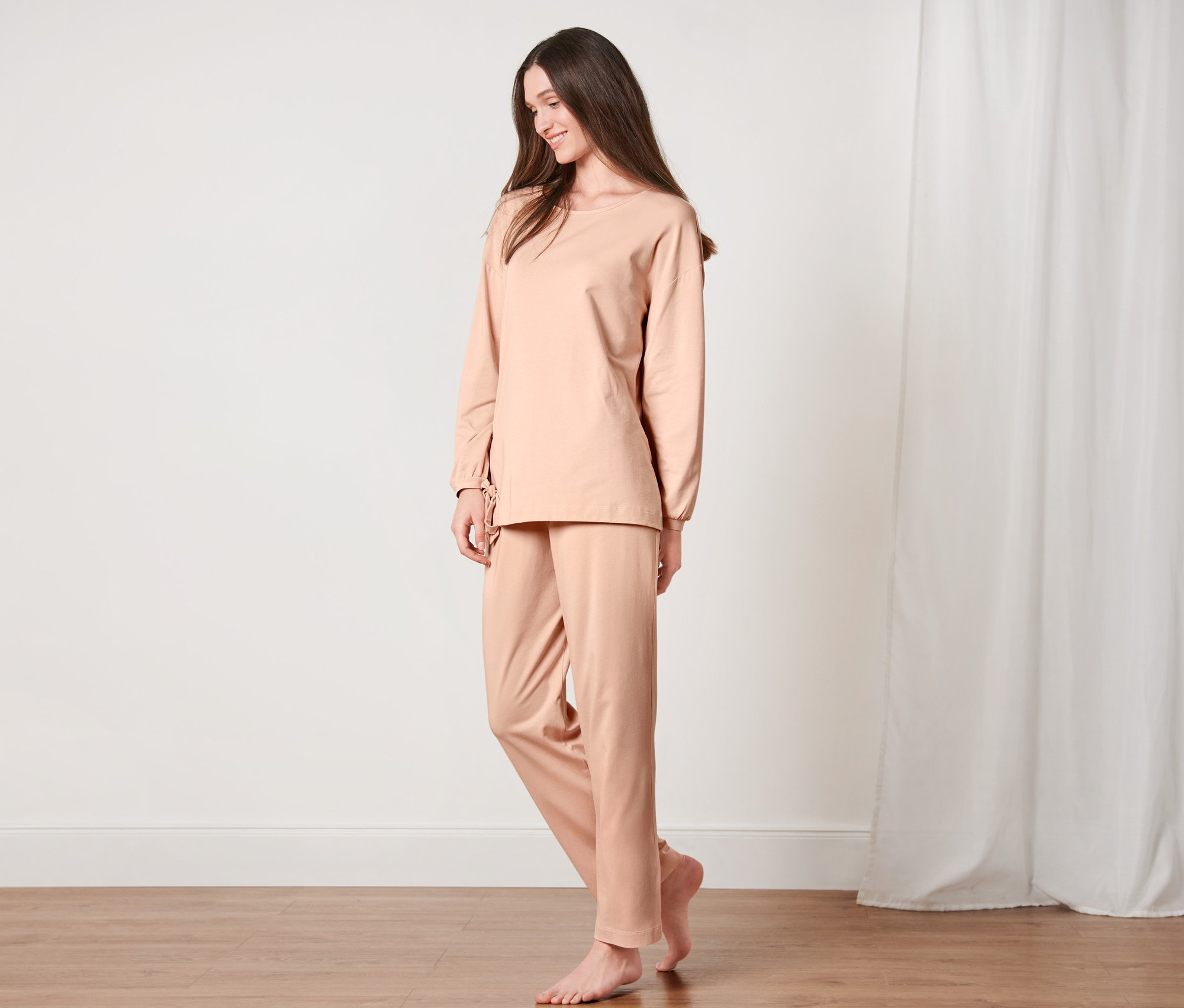 Frau steht im Pyjama im Zimmer.