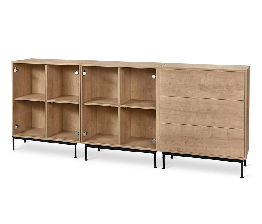 Zwei Regalmodule »Flemming« mit Glastüren und ein Regalmodul »Flemming« mit drei Schubladen in Eichendekor stehen auf einem schwarzen Fußgestell »Flemming« aus Metall.