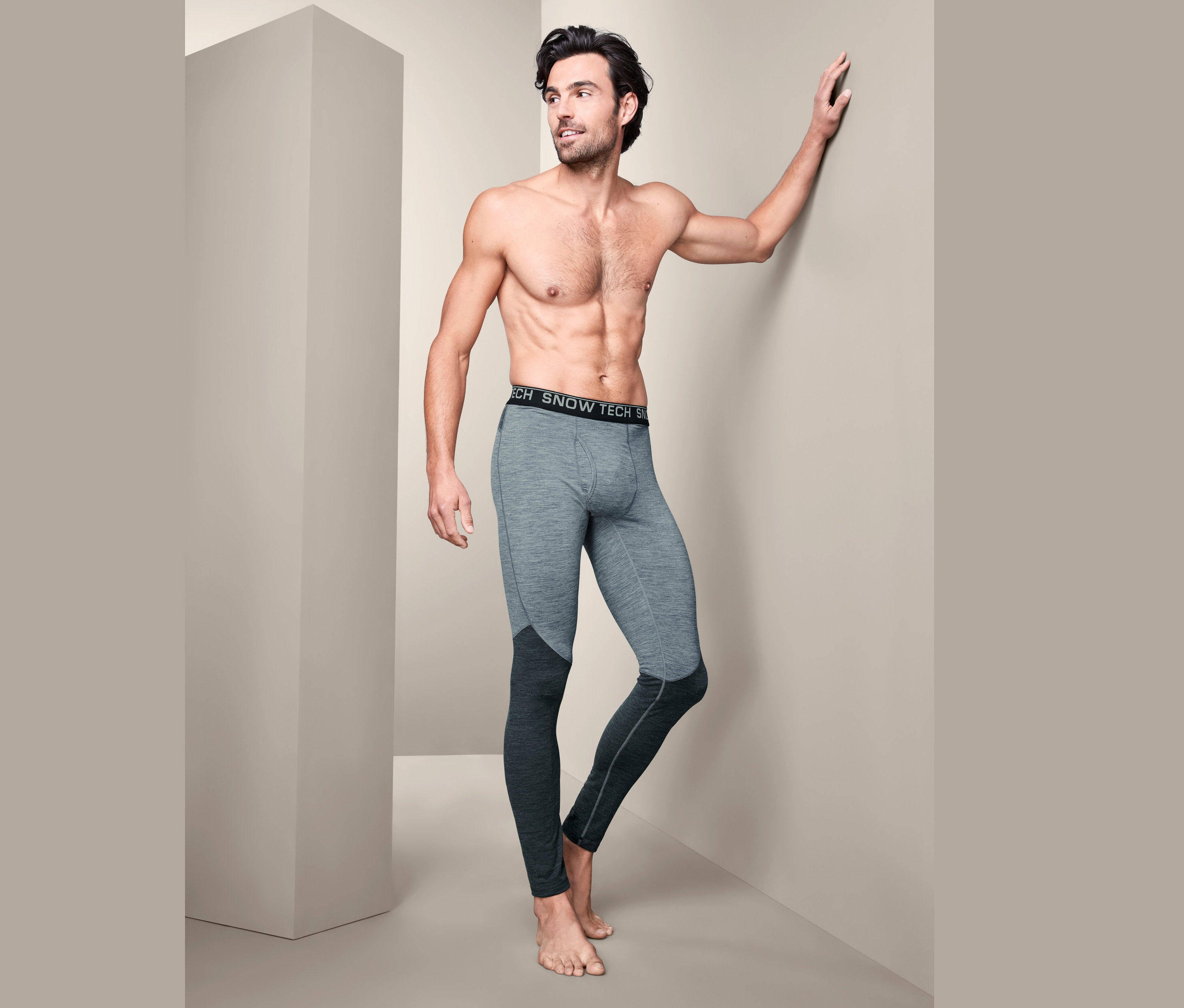 Ein Mann ohne Hemd posiert in grauen Funktionsunterhosen mit Merinowolle.