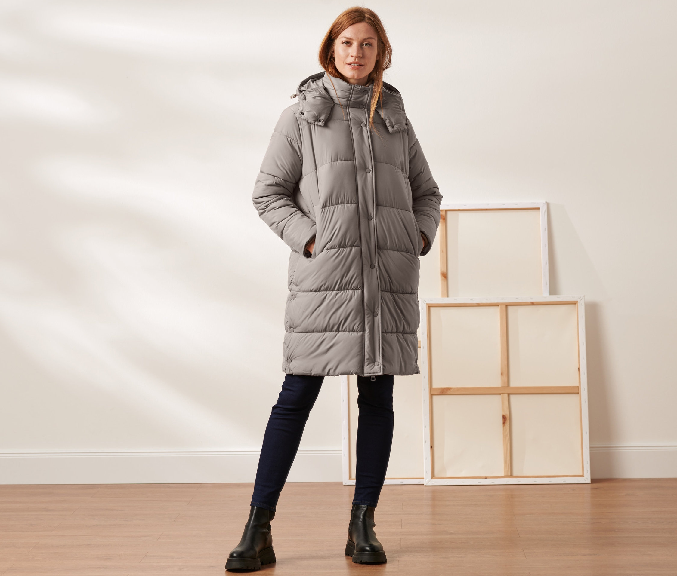 Frau trägt einen taupefarbenen Steppmantel mit Kapuze.